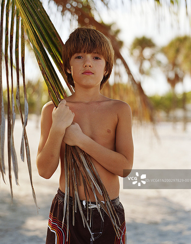 男孩(8-10)捧着挂棕榈叶，人像图片素材
