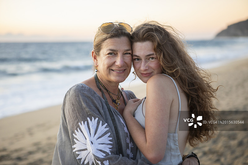 海滩上微笑的母亲和十几岁的女儿的肖像图片素材