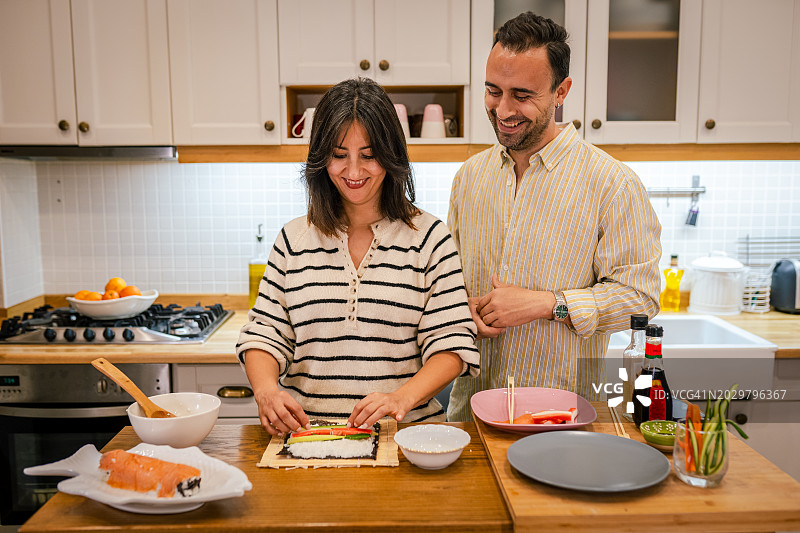 一对年轻夫妇在厨房一起做寿司图片素材