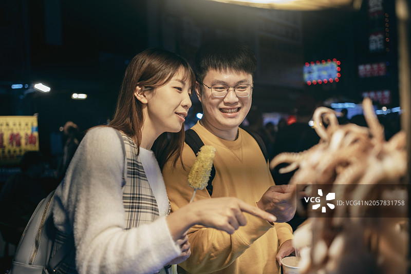 一对年轻的亚洲夫妇在台湾逛了当地著名的夜市，品尝了街头小吃图片素材