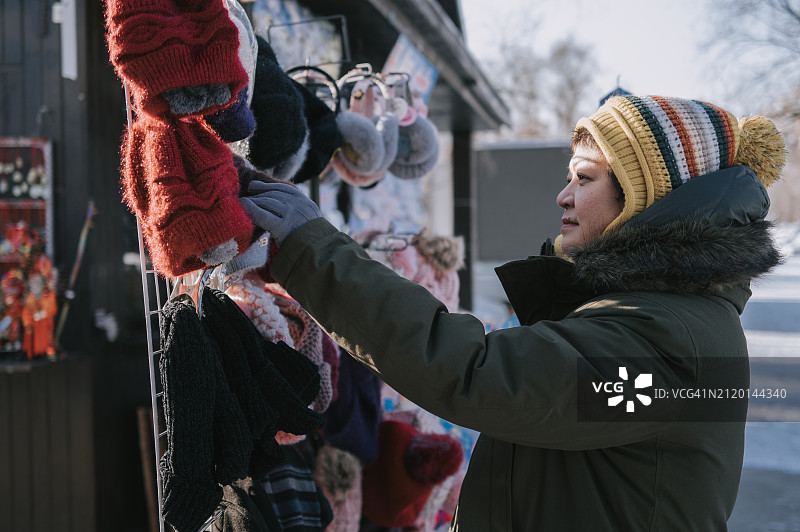 冬季，中国吉林省吉林市的市场街上，亚洲中国女游客在看针织帽图片素材