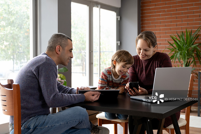 父亲、母亲和儿子在家里使用科技设备互动图片素材