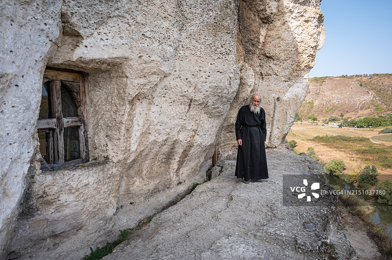 在摩尔多瓦Trebujeni的老Orhei (Orhei Vechi)洞穴修道院，东正教僧侣站在陡峭悬崖上的露台上图片素材