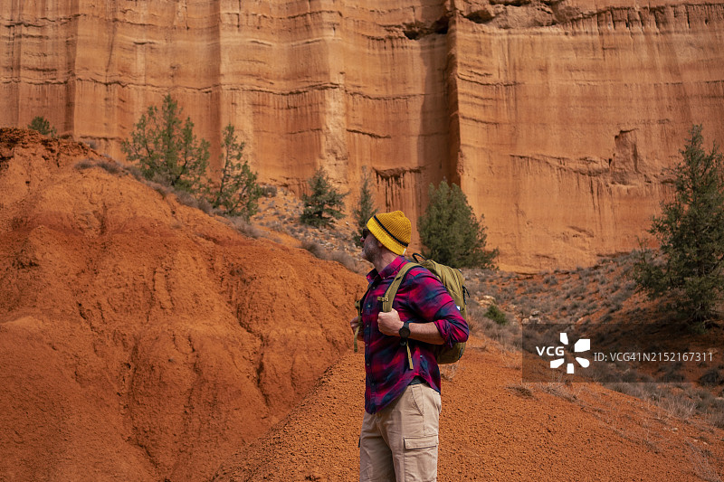 一个成熟的男人背着背包站在红峡谷图片素材
