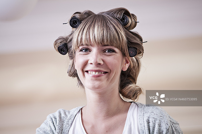 德国，北莱茵威斯特伐利亚，科隆，带着卷发器的年轻女子的肖像，微笑着图片素材