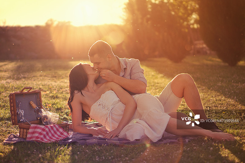 迷人的夫妇在乡村享受浪漫的日落野餐图片素材