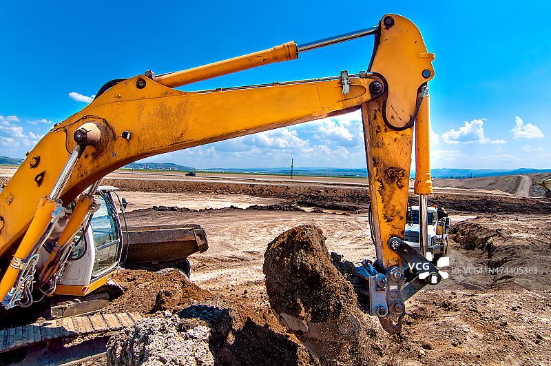 工业用挖掘机、推土机在沙坑中挖掘和装载图片素材