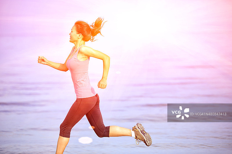 健康的生活方式女人在海滩上跑步图片素材