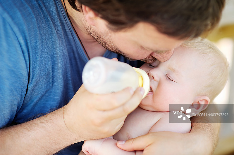 婴儿从父亲手中的奶瓶里喝牛奶图片素材
