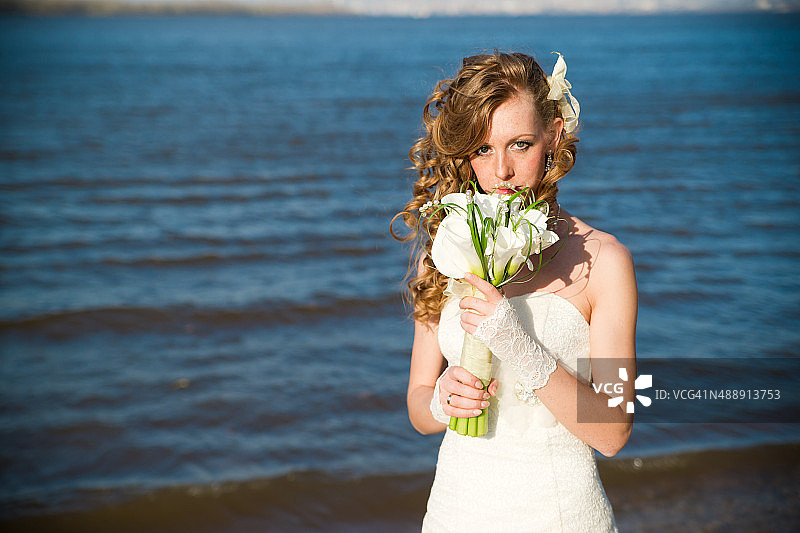 美丽的新娘捧着一束鲜花在河岸上图片素材