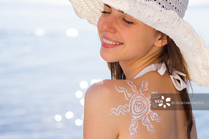 快乐的女人，阳光洒在肩膀上，在海滩上闭上眼睛放松图片素材