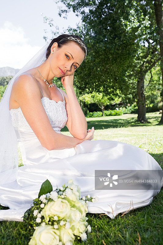 悲伤的新娘手托着下巴在花园里图片素材