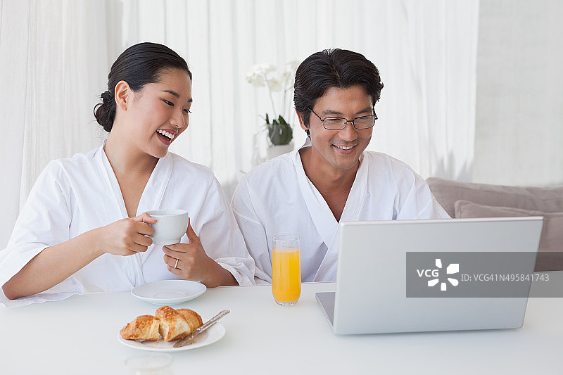 幸福的夫妇用笔记本电脑吃早餐图片素材