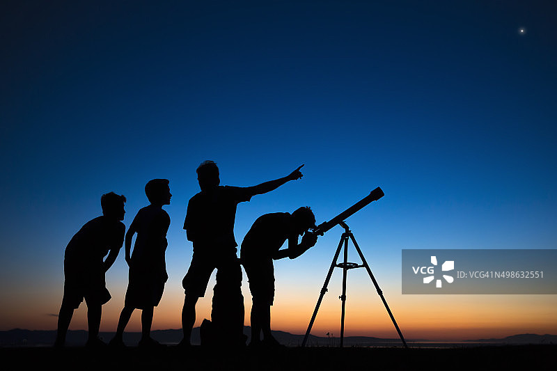 爸爸和三个儿子在用望远镜看东西图片素材