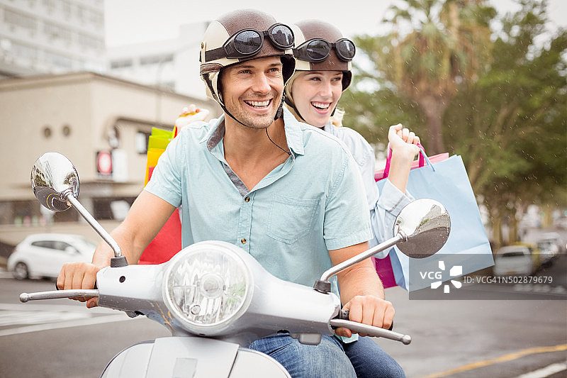 时髦的年轻夫妇骑着滑板车带着购物袋图片素材