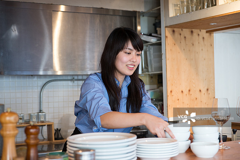 年轻的日本女士在厨房工作图片素材