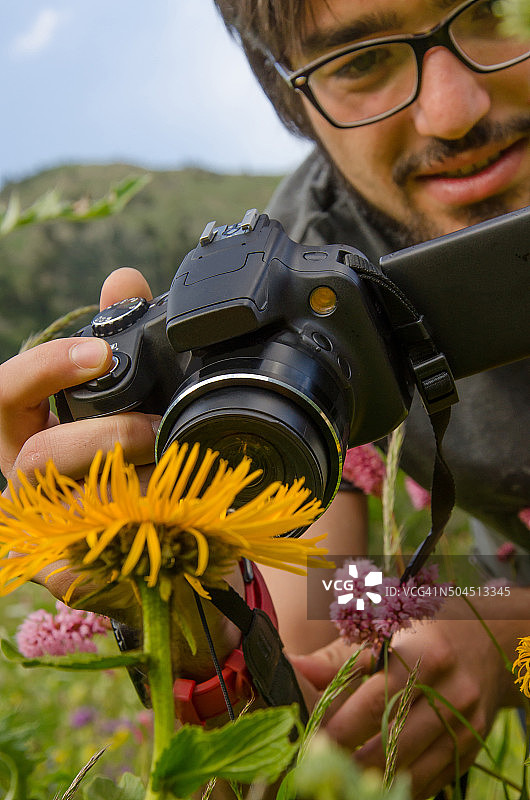 徒步摄影师在山上拍一幅花的照片图片素材
