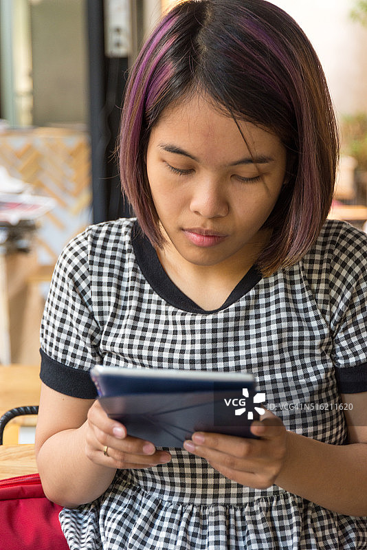 年轻的亚洲女人在用平板电脑上网图片素材