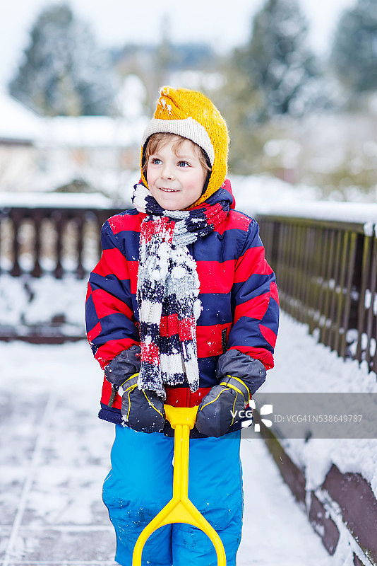 有趣的小男孩穿着五颜六色的衣服开心的在雪地里，在户外图片素材