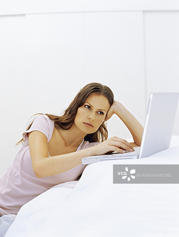 女商人躺在床上用着笔记本电脑图片素材