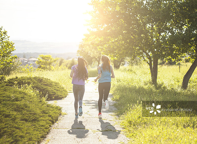 两个年轻的女运动员在公园的小道上跑步图片素材