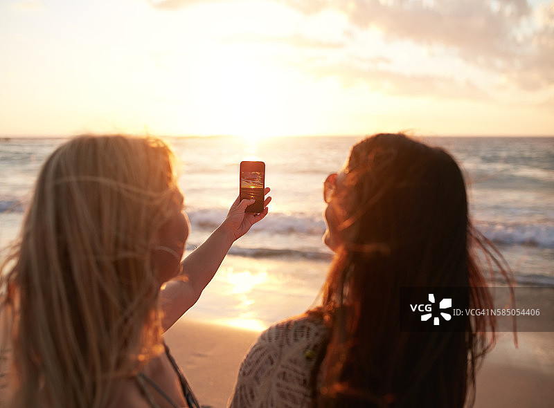 女性朋友在海滩上拍摄日落图片素材