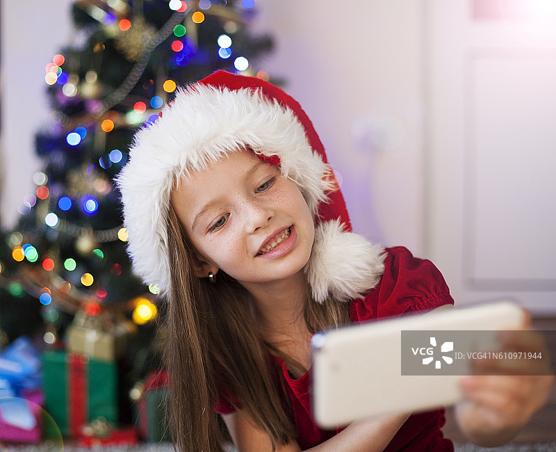 戴着圣诞帽拿着圣诞礼物的女孩，智能手机图片素材