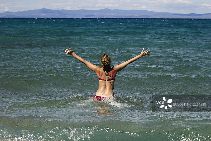 快乐的年轻女子在沙滩上玩耍奔跑图片素材