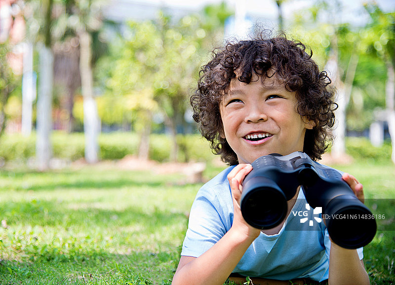小男孩拿着望远镜在公园里图片素材