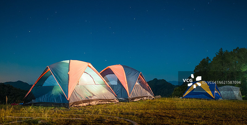 露营帐篷在繁星点点的夜空下闪闪发光。图片素材