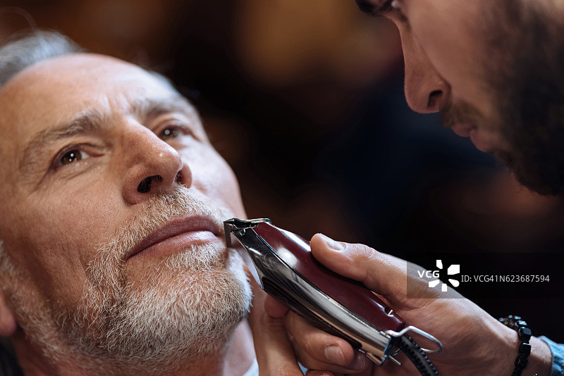 一位老人正在理发师给他刮胡子图片素材