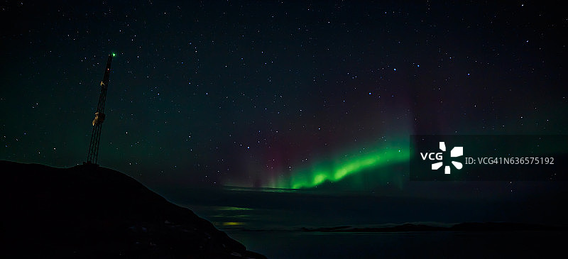 山上的无线电塔和峡湾上空的北极光图片素材