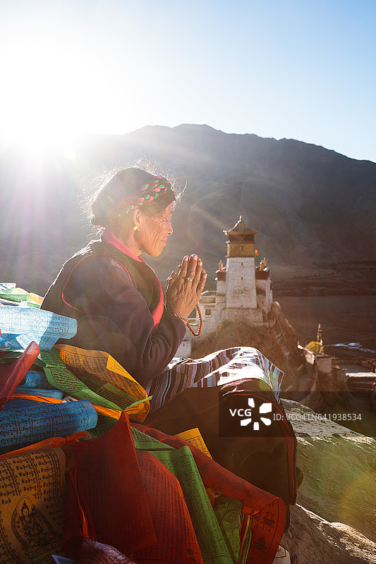 老奶奶在西藏山顶上祈祷日落图片素材