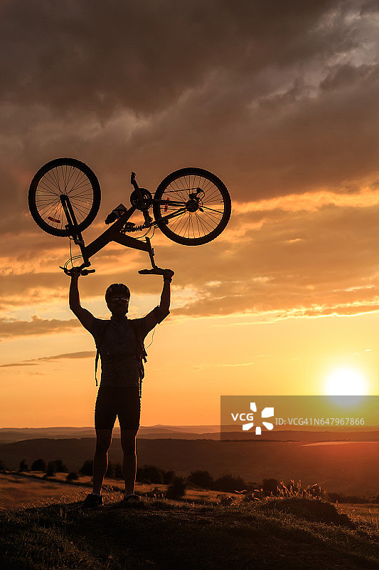 夕阳西下，一个骑自行车的人的剪影图片素材