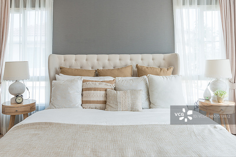 柔和的浅色卧室。舒适的大双人床在优雅的古典卧室在家里。图片素材