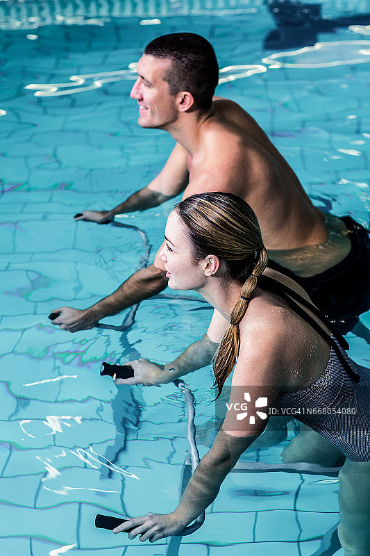 微笑的情侣在游泳池里骑车图片素材