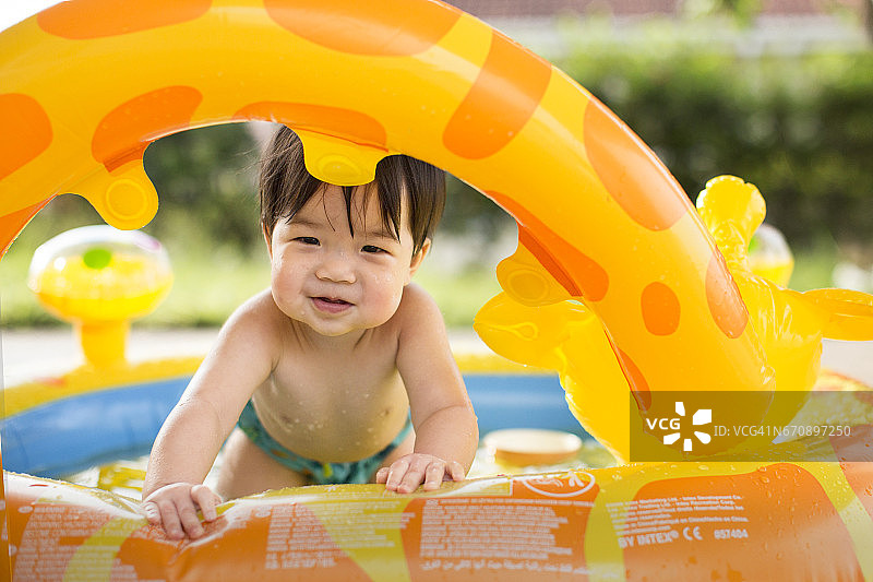 亚洲幼童在充气泳池里看起来很开心。图片素材