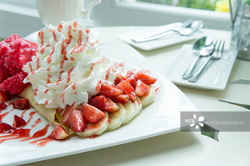 冰淇淋草莓可丽饼甜点在咖啡厅的白色碟木桌上图片素材