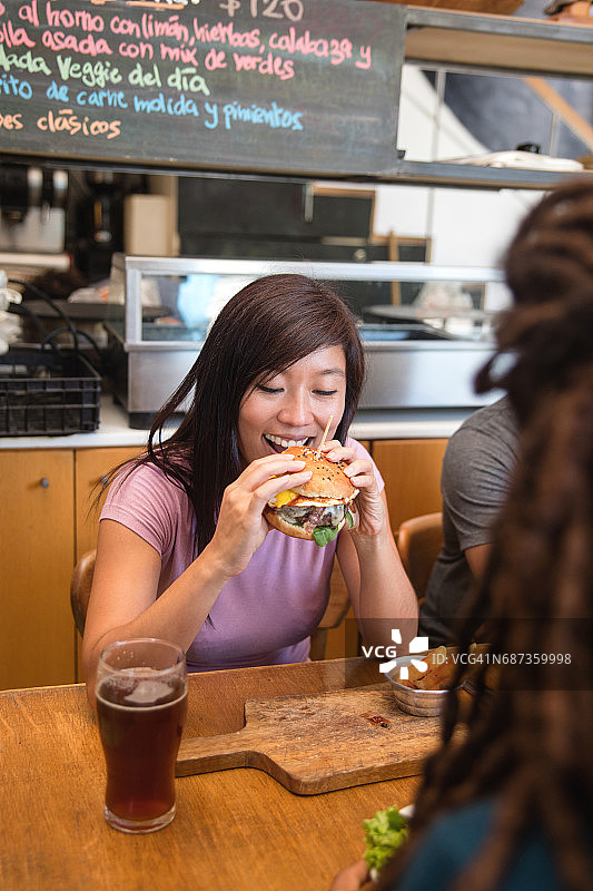 在餐厅吃汉堡的快乐女人图片素材