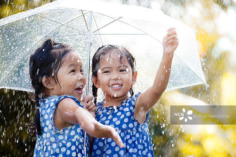 两个快乐的亚洲小女孩带着伞一起玩雨图片素材