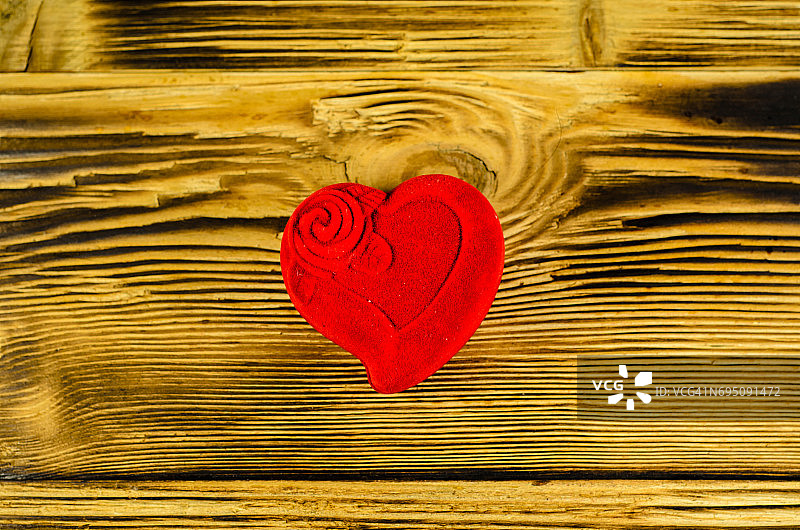 红色的心形首饰盒放在一张木桌上。俯视图图片素材
