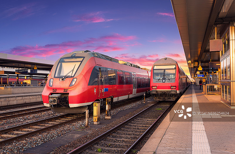美丽的红色通勤列车在火车站和彩色天空日落在欧洲。工业景观与美丽的铁路站台和现代列车在夏季。铁路。铁路旅游图片素材