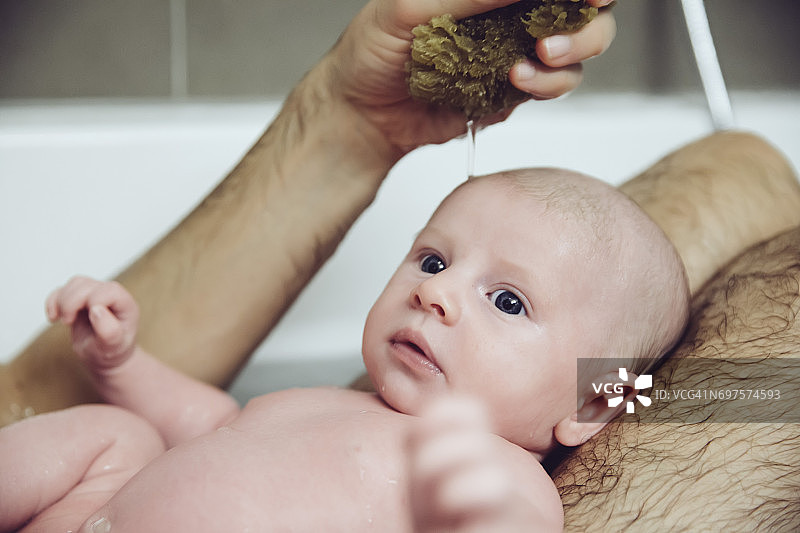 爸爸和宝宝在用天然海绵洗澡图片素材
