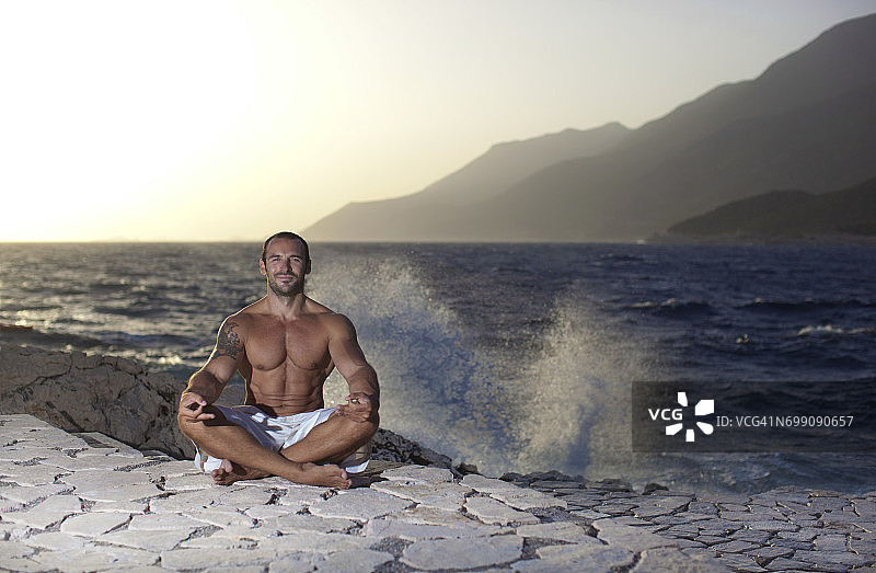 在海边，一个肌肉发达的男人正在做瑜伽图片素材