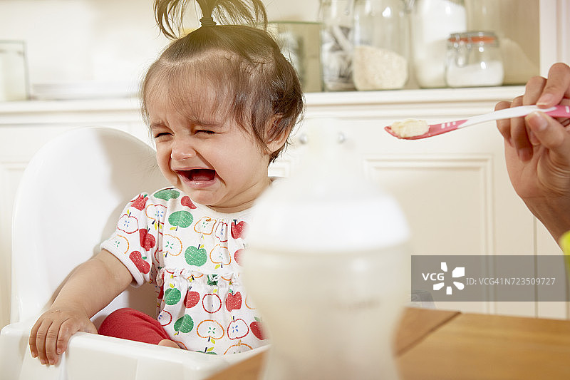 女婴在妈妈喂早餐时哭泣图片素材
