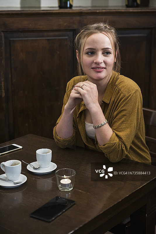 年轻女子坐在餐厅的餐桌旁图片素材