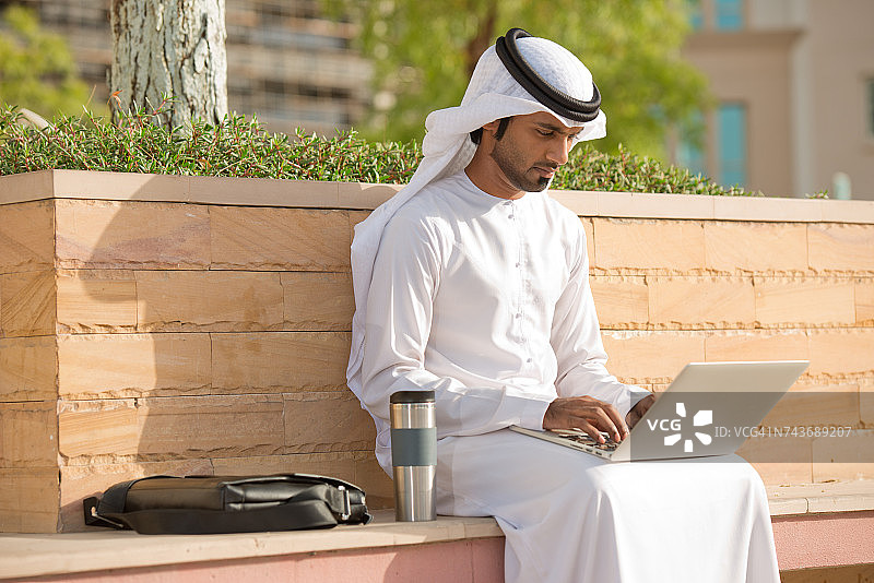 一个阿联酋商人在用笔记本电脑工作。一位阿联酋商人在用笔记本电脑工作。图片素材