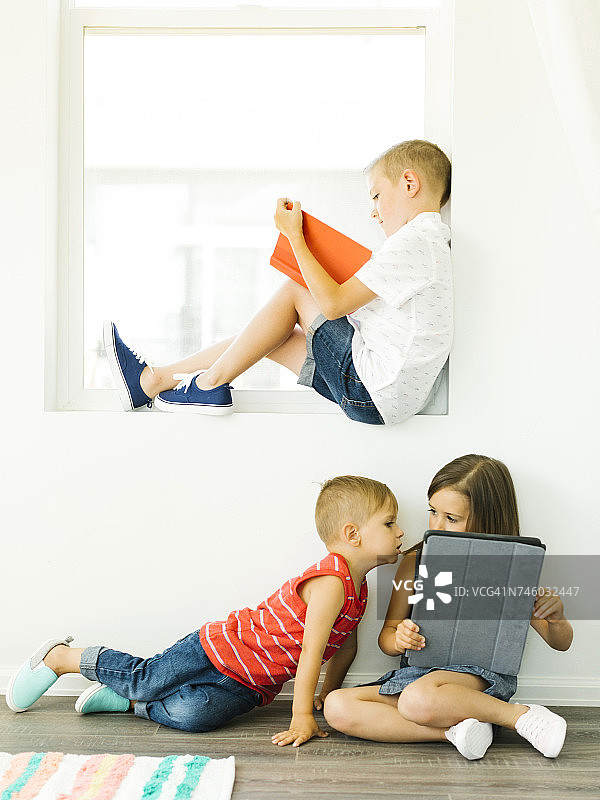 男孩(6-7)在看书，妹妹和弟弟(2-3,6-7)在用数码平板电脑图片素材