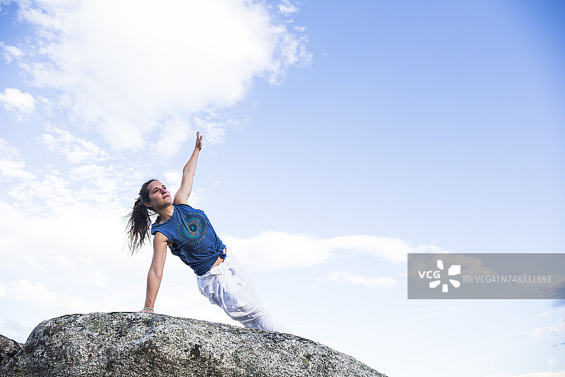 一个女人在岩石上做瑜伽图片素材