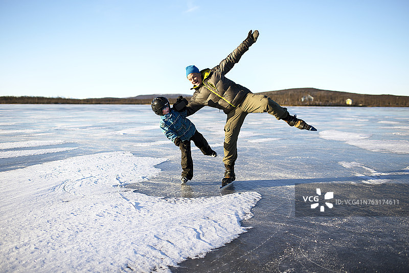 父亲和儿子在结冰的湖面上滑冰图片素材